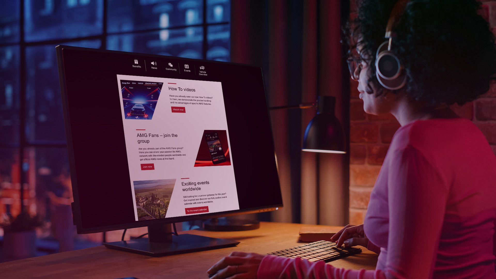 A woman sits on a desk with a keyboard in front of a screen that shows the content of the Mercedes-AMG newsletter